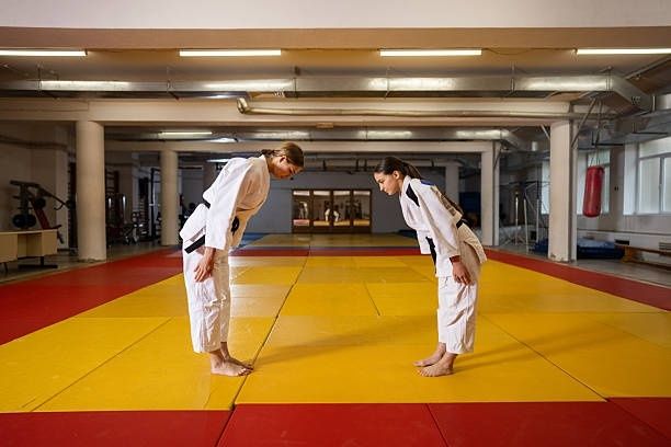 Zwei Judoka verbeugen sich auf einer gelb-roten Matte im Dojo