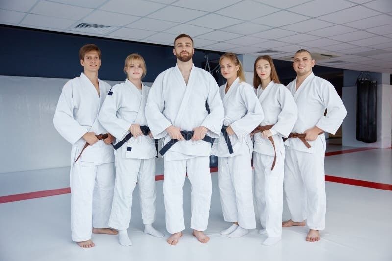 Sechs Aikido-Trainierende stehen aufrecht im weißen Gi im Dojo