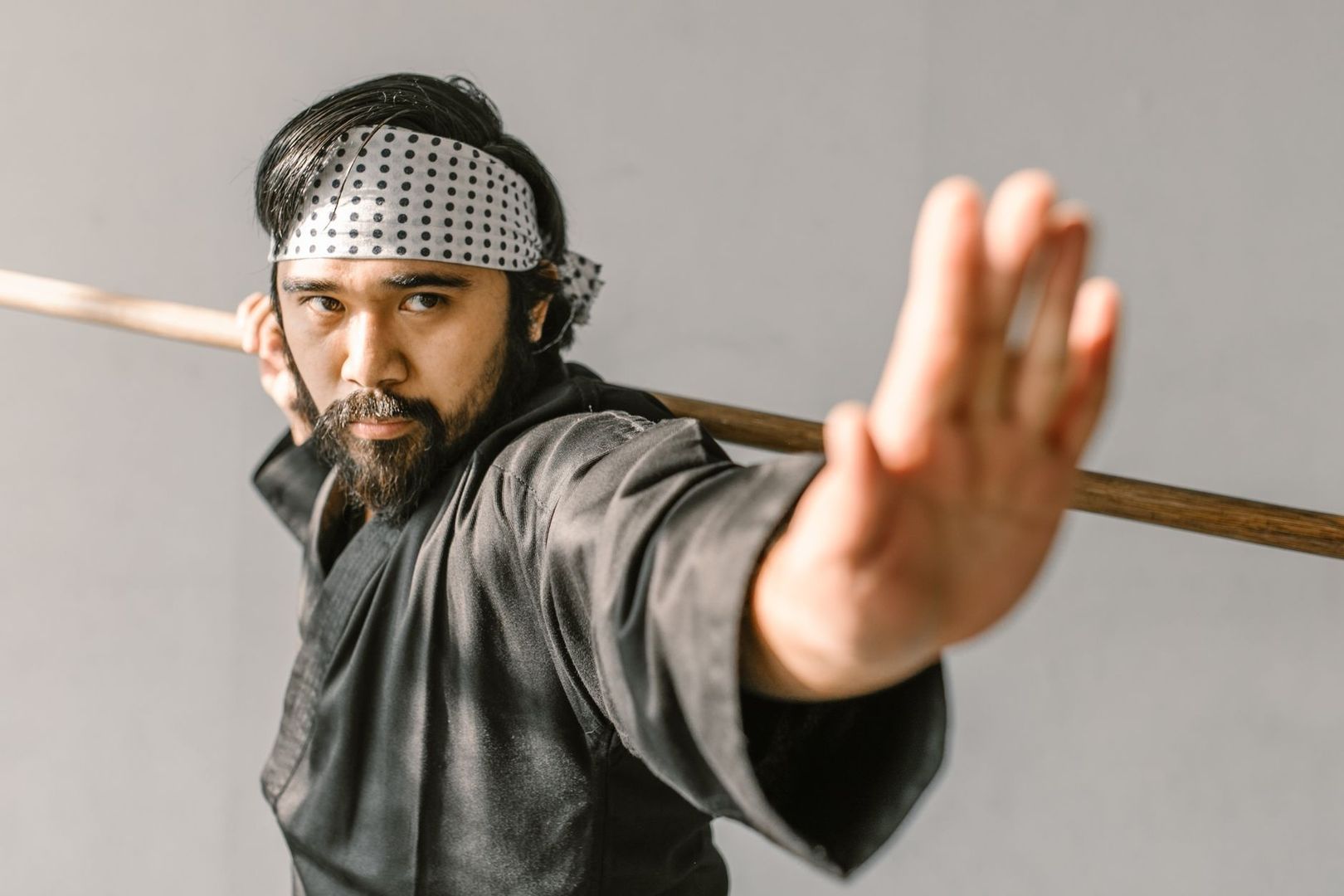 Kampfsportler mit Holzstab und erhobener Hand in Trainingspose